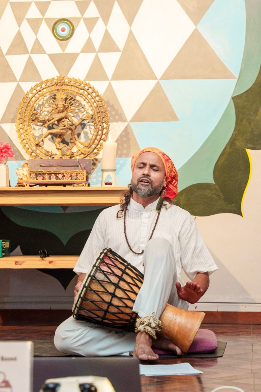 Anup spielt eine Handtrommel und singt in einer Meditationshalle